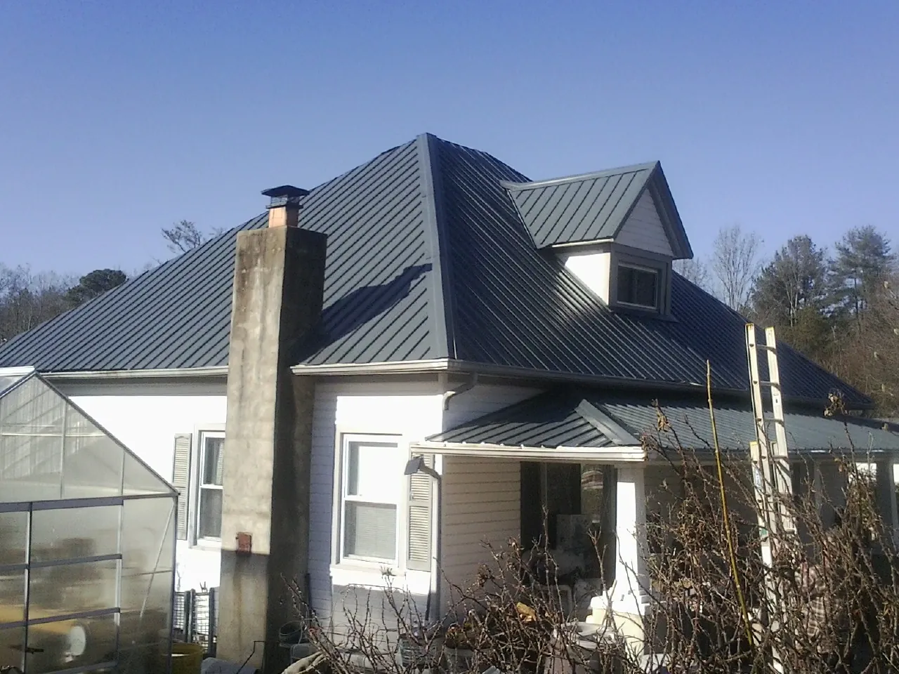Dark blue standing seam metal roof on a white farmhouse with dormer — Slate & Tile Roof Repair by Roofing Brothers in West Frankfort