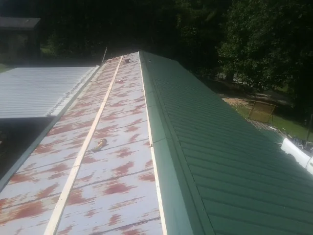 Old rusted panels beside newly installed green metal roofing — Wind Damage Roof Repair by Roofing Brothers in West Frankfort