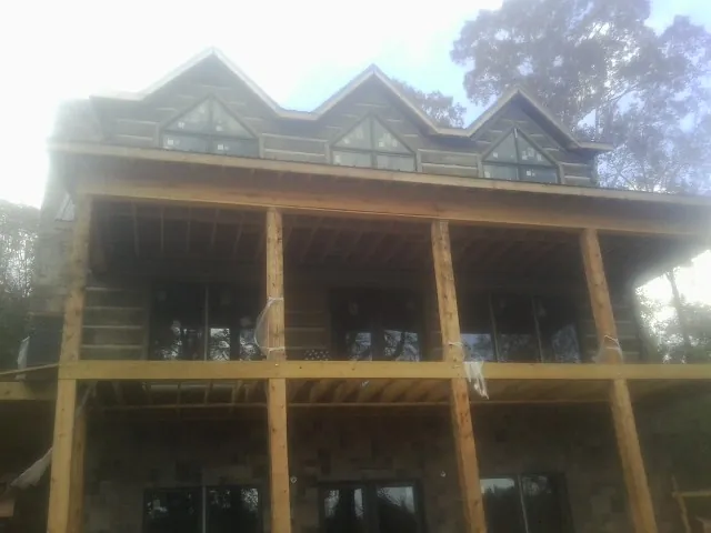 Dormers and porch framing on a large log home under construction — Roof Coating work by our crew in West Frankfort
