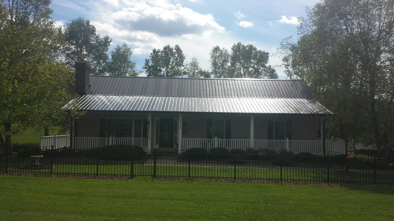 Gray metal roof on a brick ranch with a full width front porch — Gutter Guard Installation work by our crew in West Frankfort