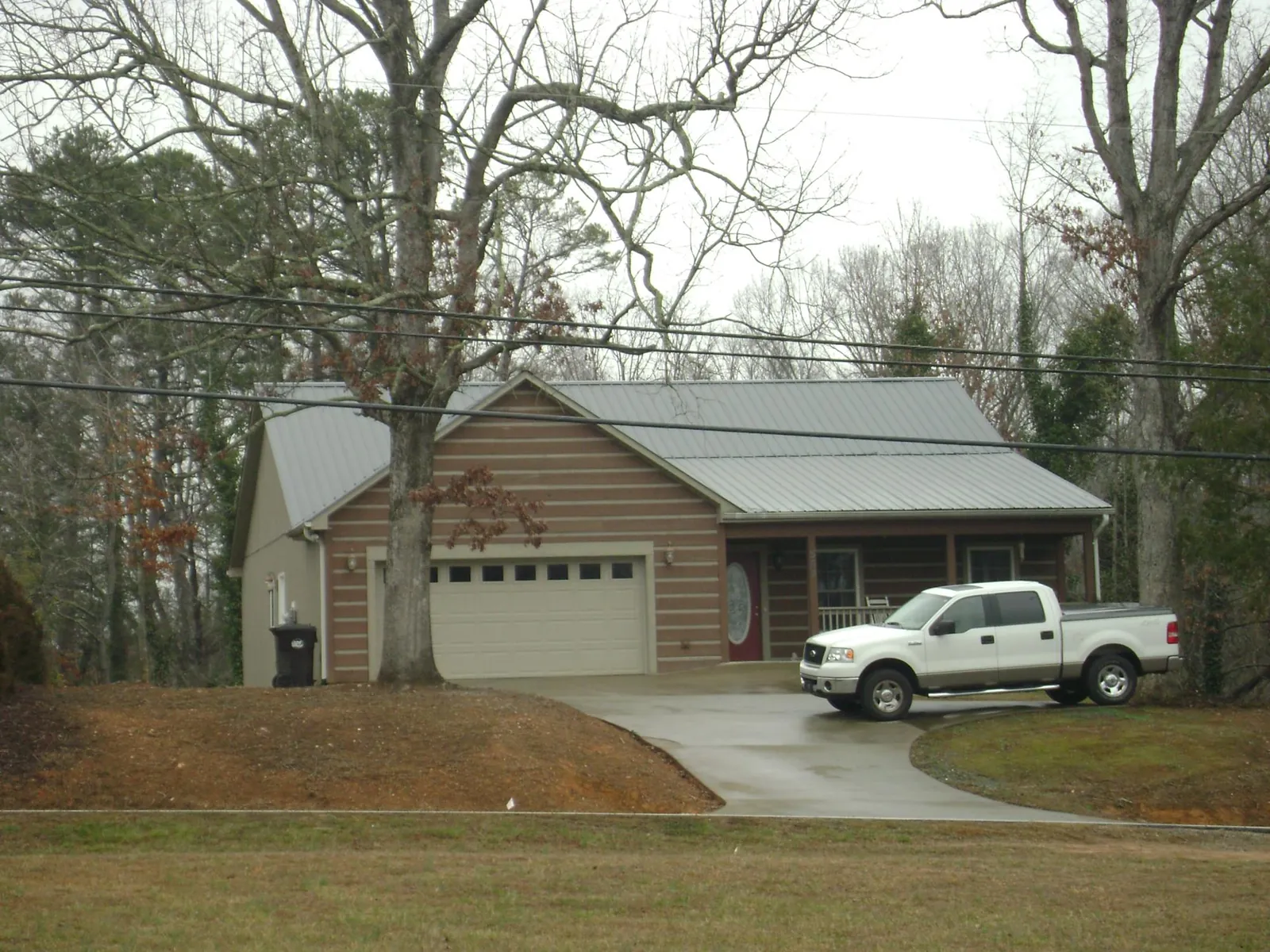 Gray metal roof on a log sided house with an attached two car garage in West Frankfort