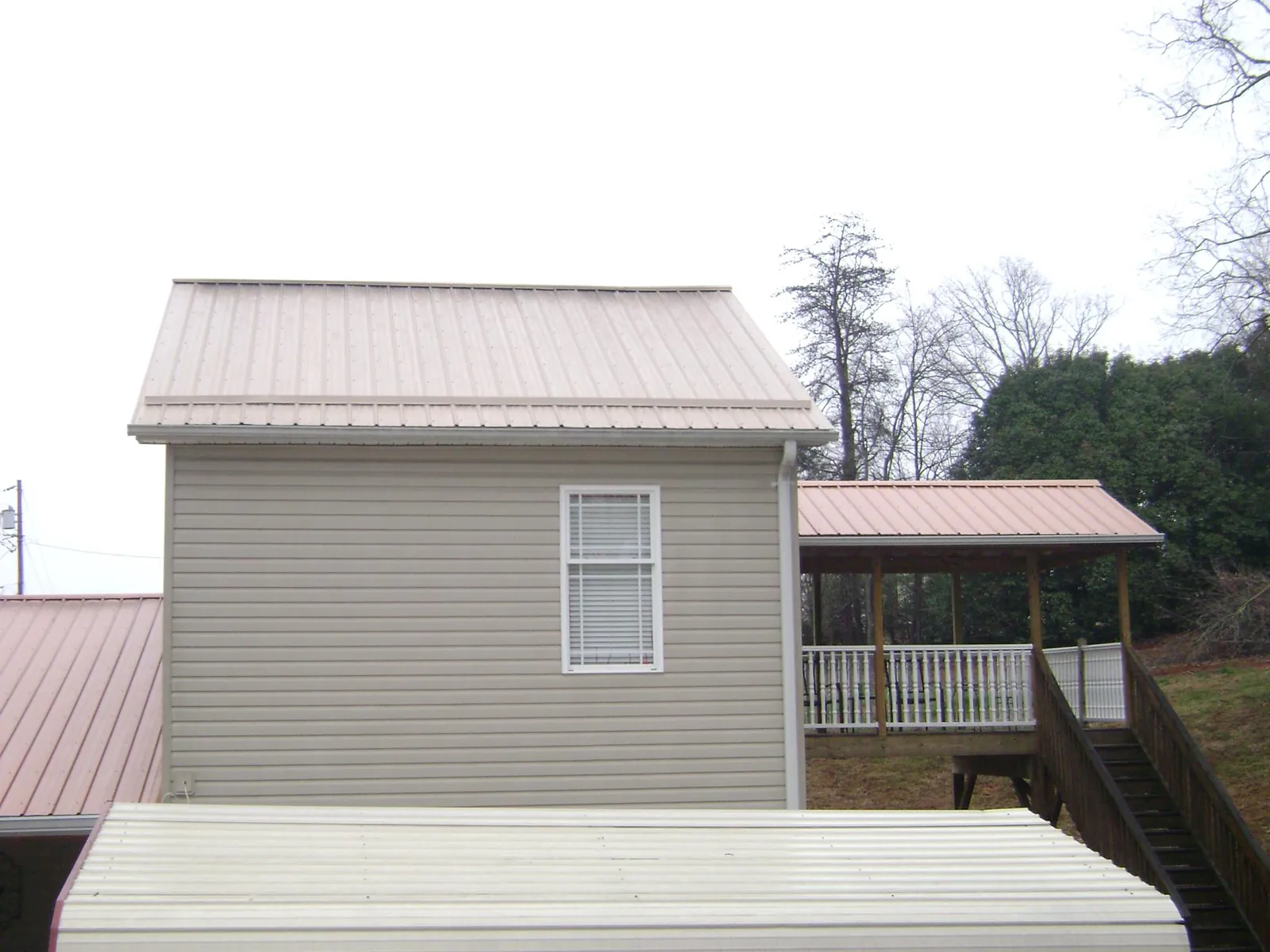 Tan metal roofs on a two story addition and attached porch, from a Roof Replacement job in West Frankfort