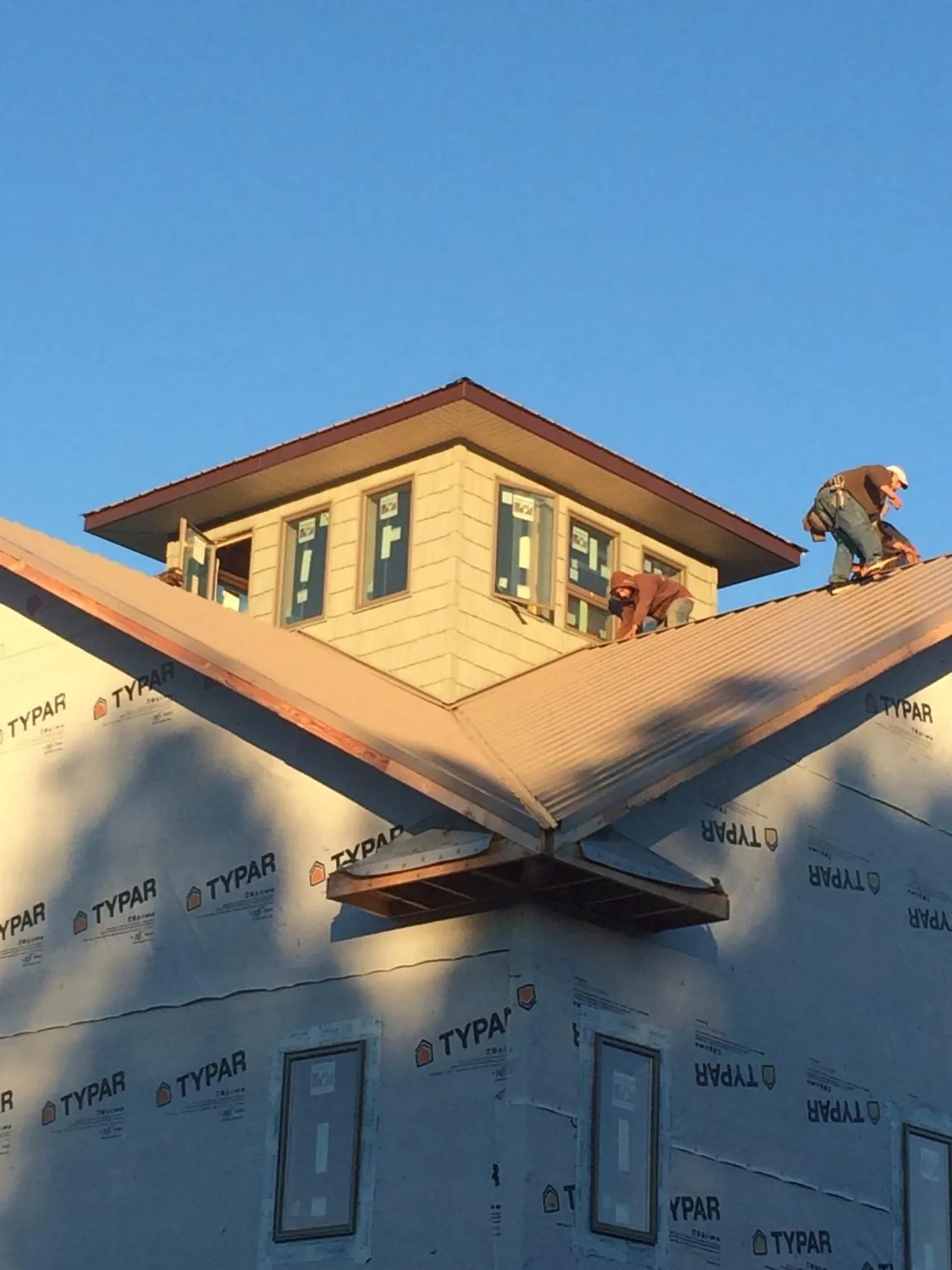 Roofers working around a rooftop cupola on a new metal roof at sunset — Roof Waterproofing in West Frankfort by Roofing Brothers